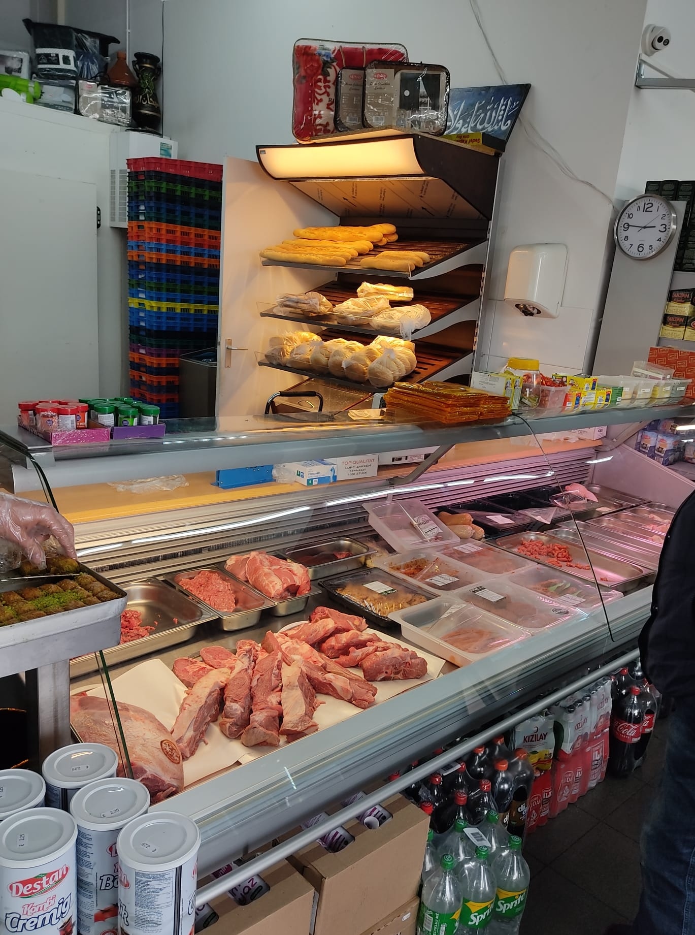 De toonbank van de slagerij met vers vlees in de koeling en het broodrek erachter